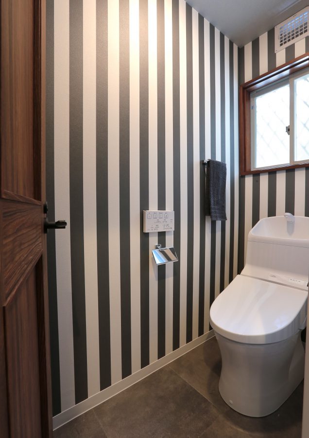 ストライプの壁で仕上げたトイレ。ラスティックな木扉ともとても良い相性。