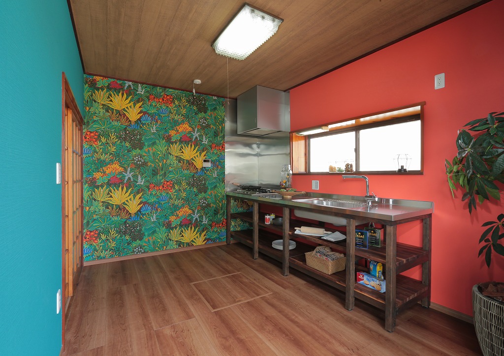 お施主様イチ押しの一際目を惹くボタニカルな壁紙を施したキッチン。左右の壁にも原色を使い、まるで異国にいるような空間に。